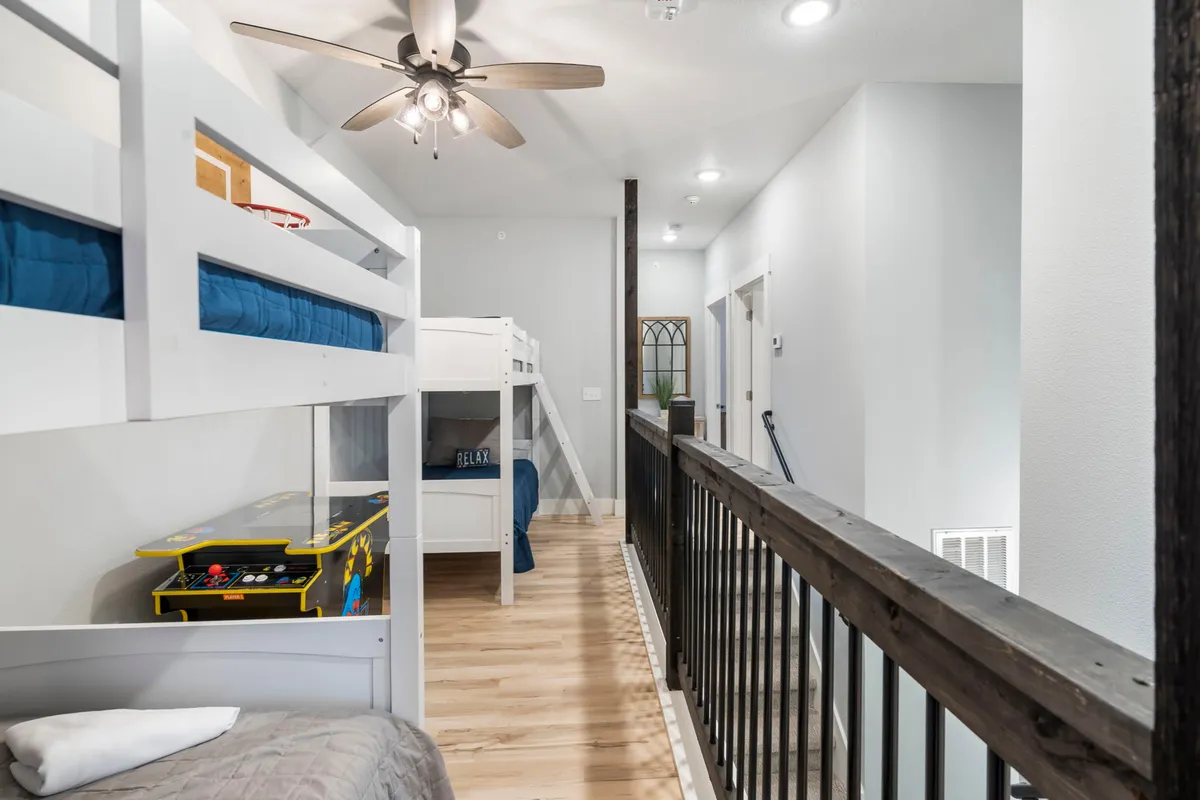 This interior shot captures a playful and relaxed space featuring twin bunk beds, a game table, and a wooden railing. The overall mood is cheerful, with the area clearly designed for entertainment and sleepovers, making it ideal for families and groups of children.
