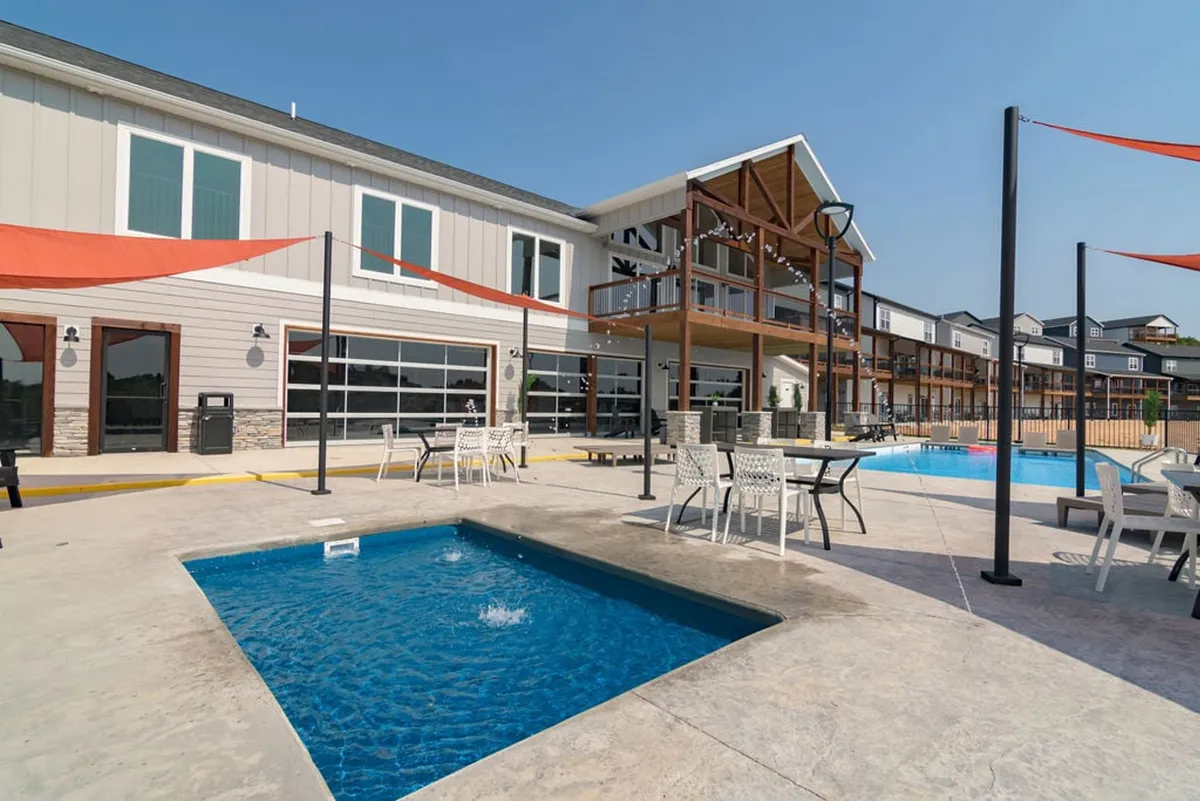 A stylish exterior pool area with a sparkling swimming pool, spa section, comfortable seating, and decorative canopies. The mood is relaxed, with the space inviting guests for social gatherings or quiet afternoons by the water.