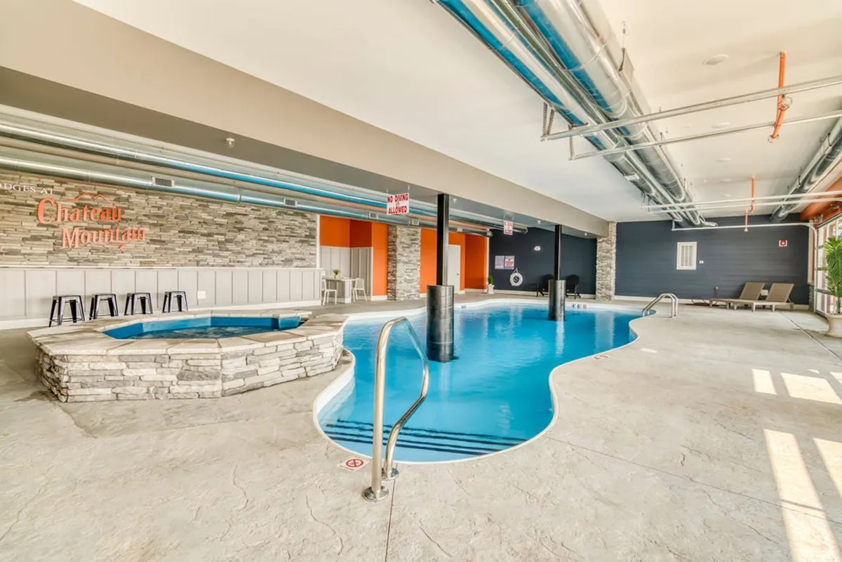 A welcoming indoor pool and hot tub area with a stone wall and comfortable seating, set in a tranquil, upscale environment. The space is designed for relaxation and socializing after a day of adventure.