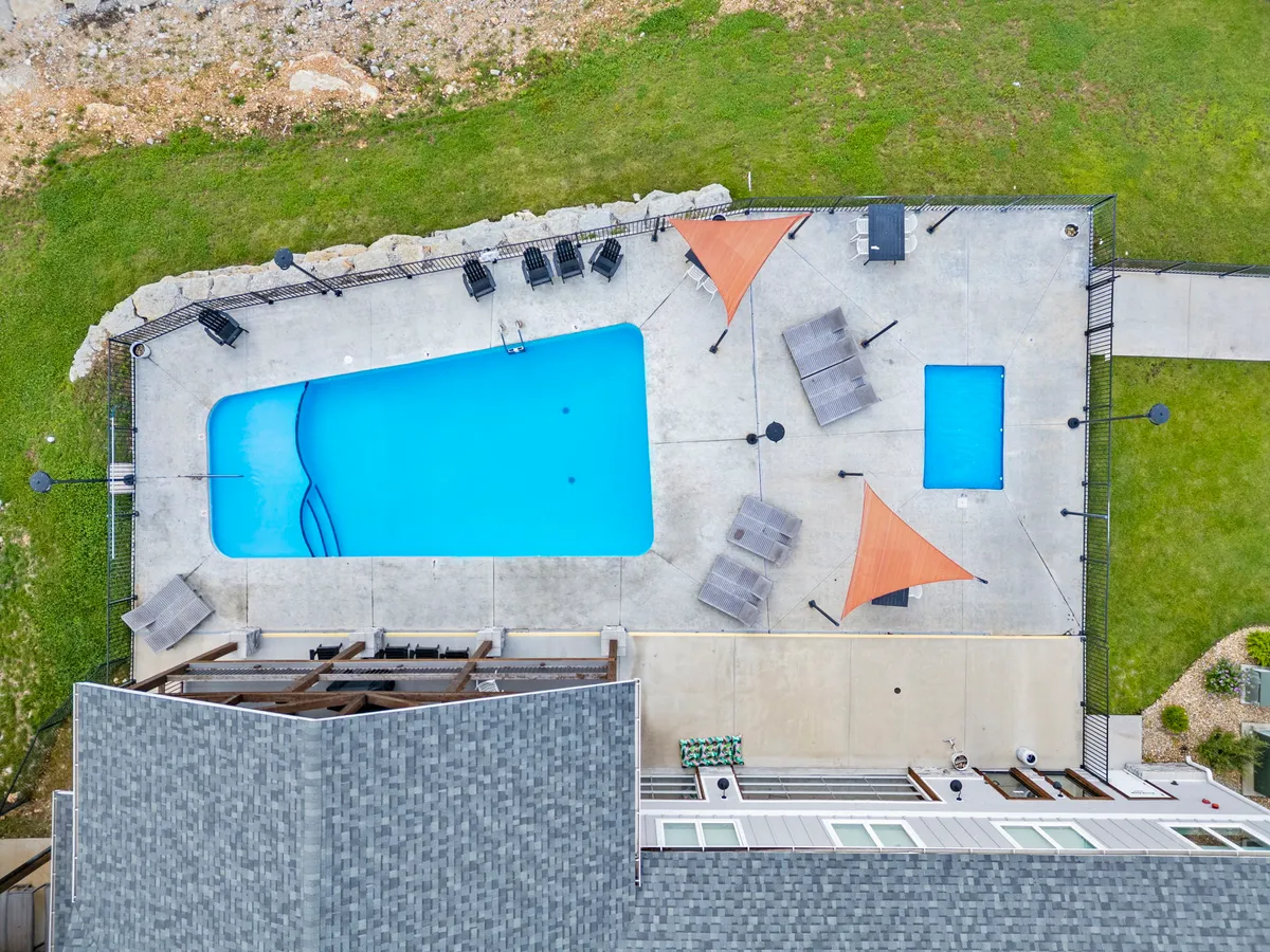 A relaxed exterior scene highlighting a sparkling swimming pool with lounge chairs and shade sails, ideal for both sunbathing and group fun. The tranquil atmosphere hints at shared amenities for guests to enjoy together.