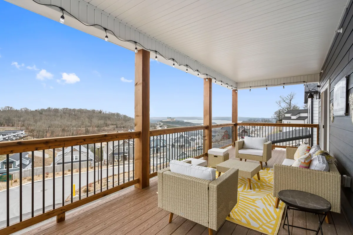 A comfortable outdoor seating arrangement sits atop a deck, complemented by a colorful area rug and panoramic landscape views. The space is designed for relaxation, socializing, and soaking up the tranquility of the surroundings. The inviting arrangement encourages guests to enjoy morning coffees or evening conversations while immersed in nature.